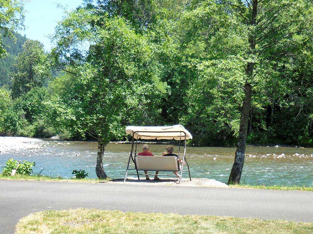 Couple sitting by the water at CASEY'S RIVERSIDE RV PARK