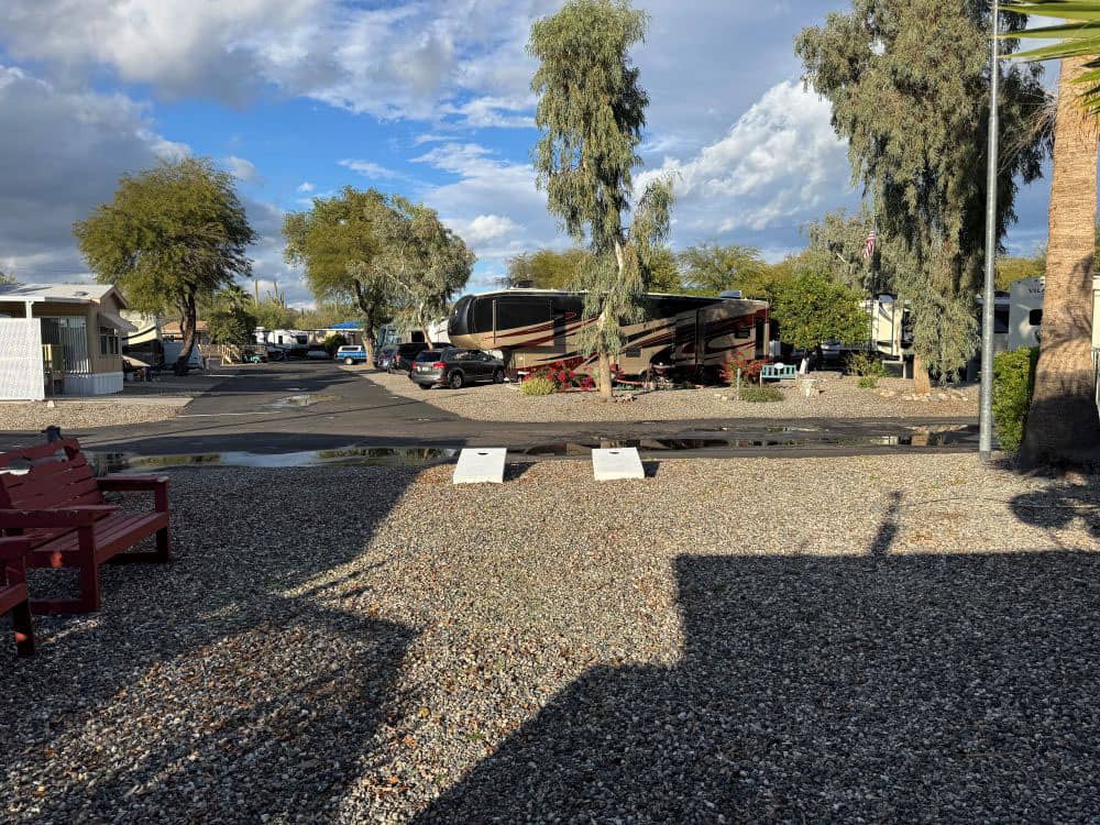 Two cornhole boards and a bench for viewing