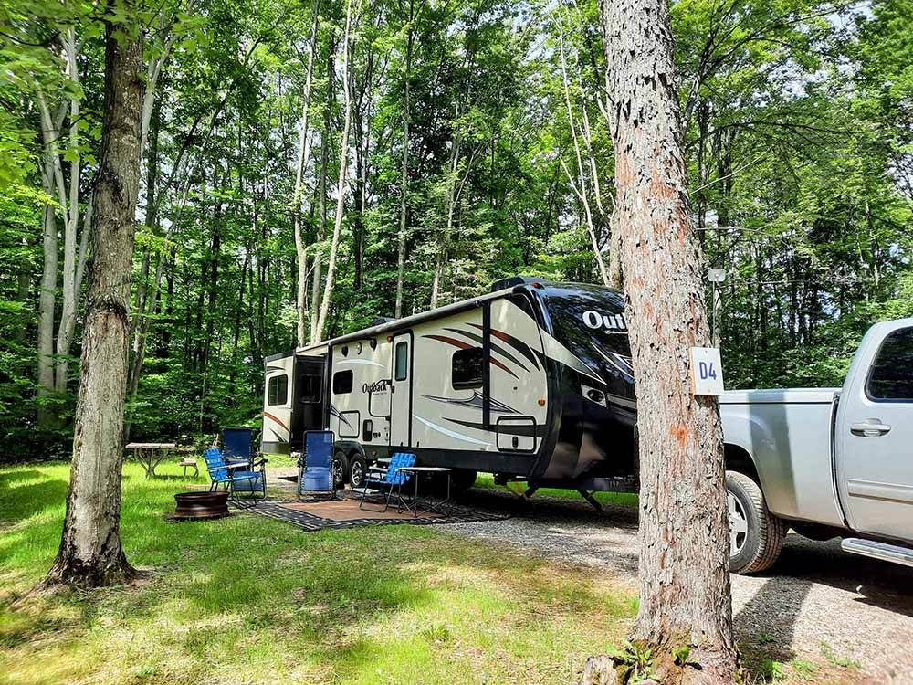 A fifth wheel trailer and truck in back in site at KALKASKA RV PARK & CAMPGROUND