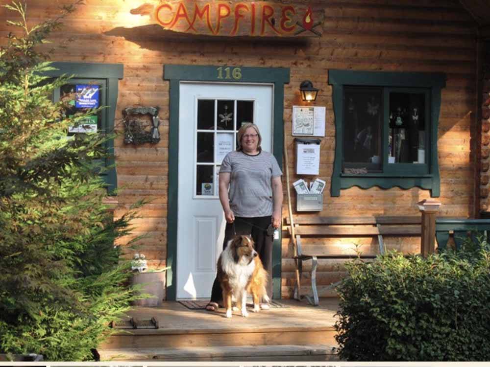 A woman and a dog standing by a door at CAMPFIRE LODGINGS