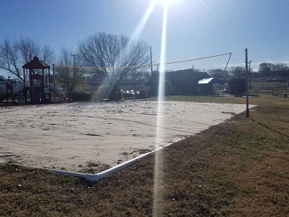 Sand volleyball court beside playground with sun at high noon at CAMPING WORLD RACING RESORT