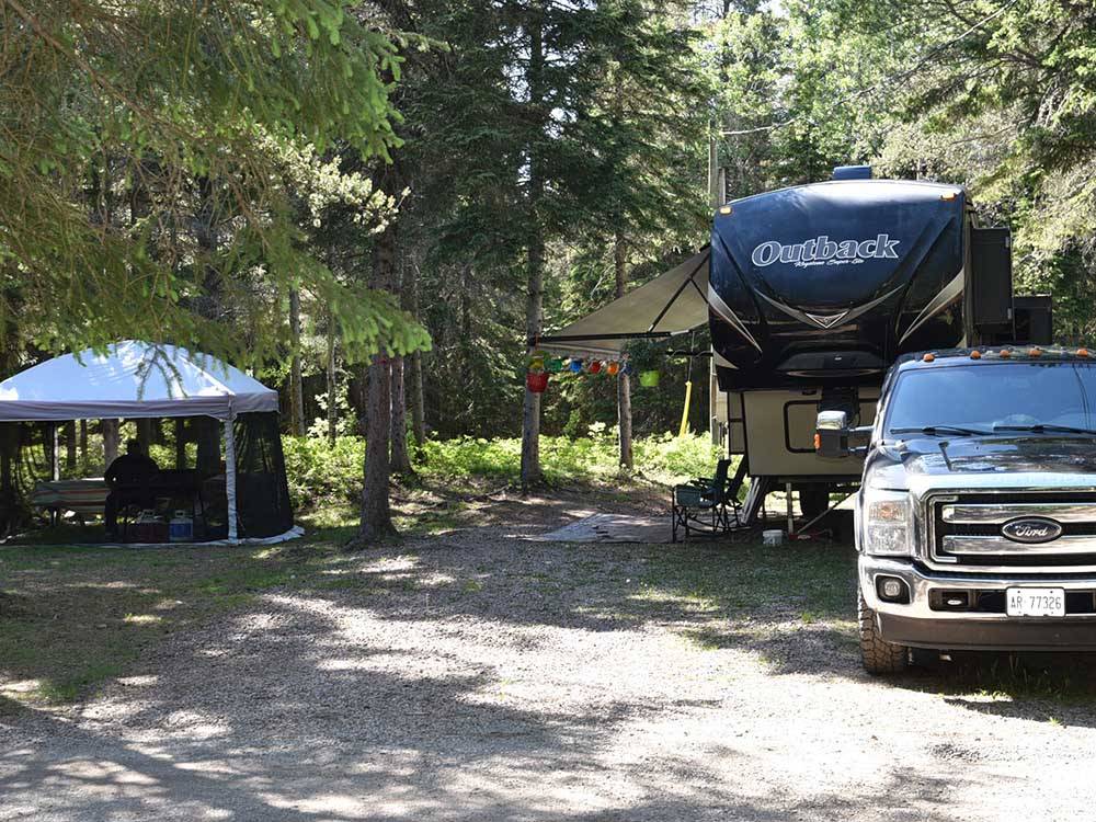 Camper and screened tent in campsite at WAWA RV RESORT & CAMPGROUND