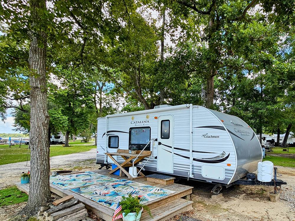 Travel trailer parked at a shaded site at Taw Caw Campground & Marina