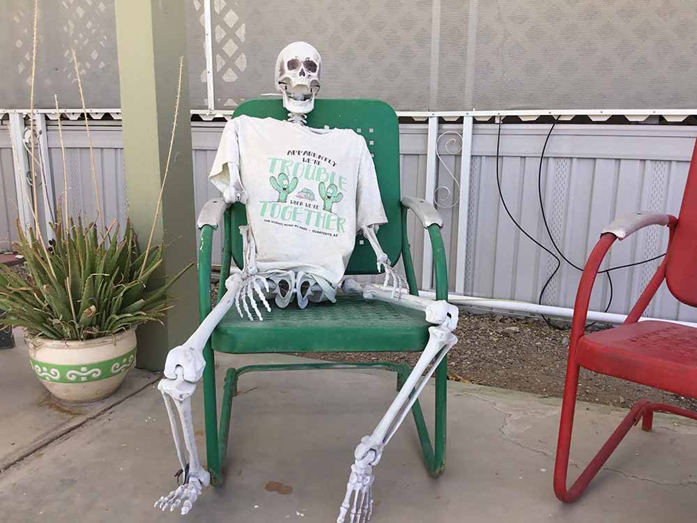 A fake skeleton sitting in a chair at THE SCENIC ROAD RV PARK