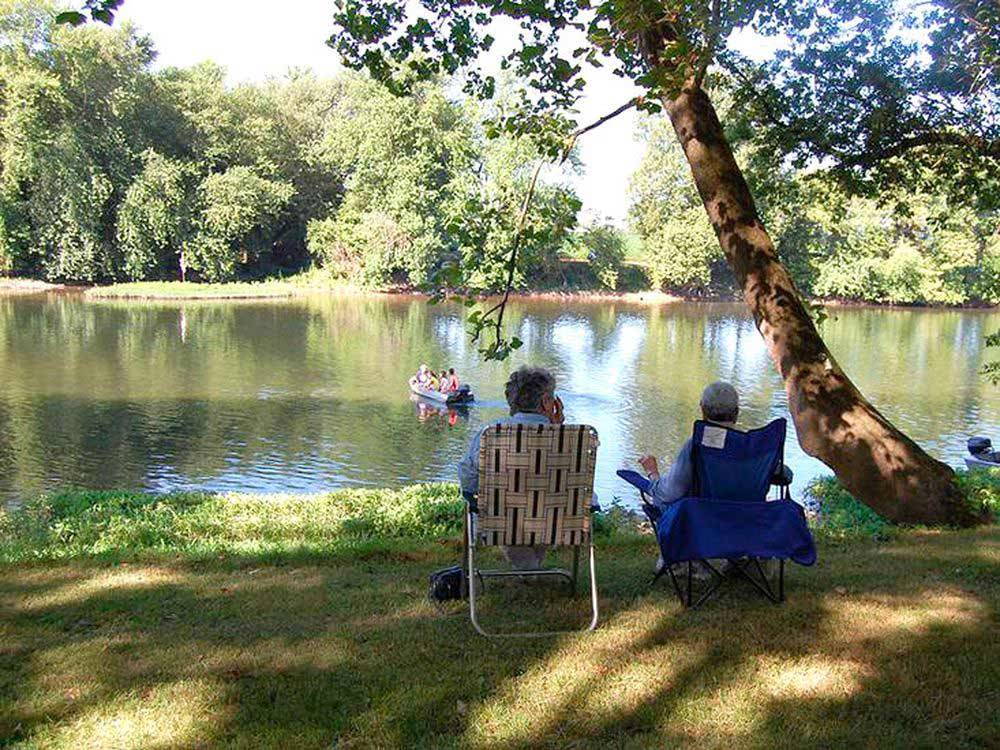 Couple sitting by the water at WATERSIDE CAMPGROUND & RV PARK