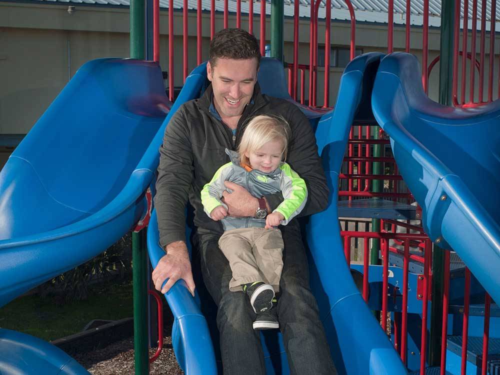 A man and child on the playground equipment at DELLANERA RV PARK