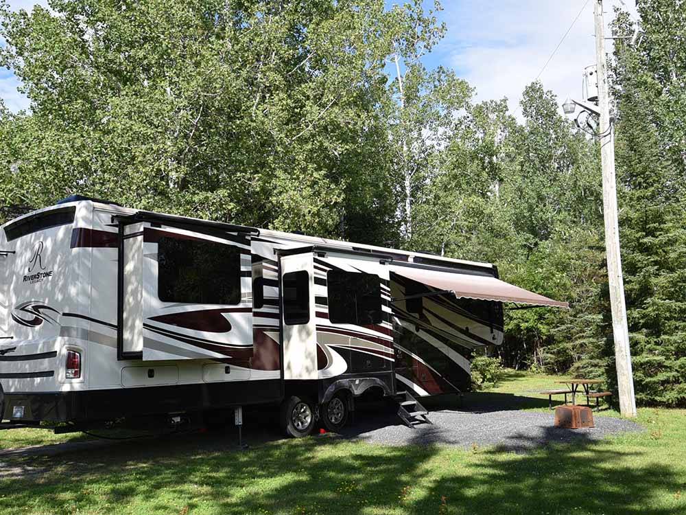A fifth wheel trailer in a grassy RV site at THE WILLOWS RV PARK & CAMPGROUND