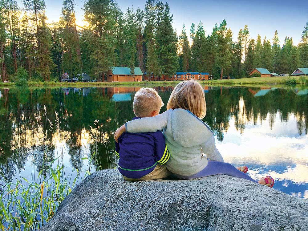 Kids sitting on a rock by the lake at THOUSAND TRAILS LEAVENWORTH