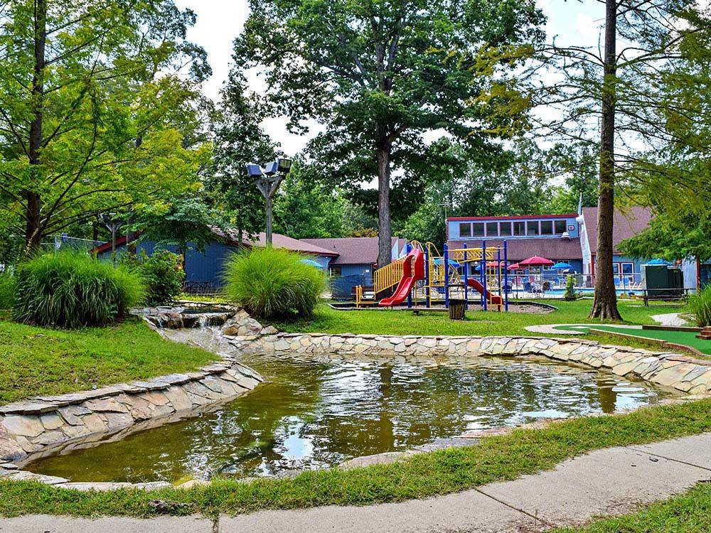 Playground with pool and pond nearby at THOUSAND TRAILS WILLIAMSBURG