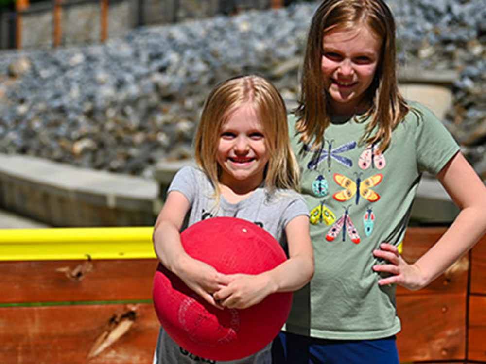 A couple of kids holding a red ball at STONYBROOK RV RESORT