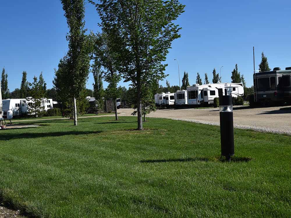 A grassy area next to the gravel road at CAMP 'N CLASS RV PARK