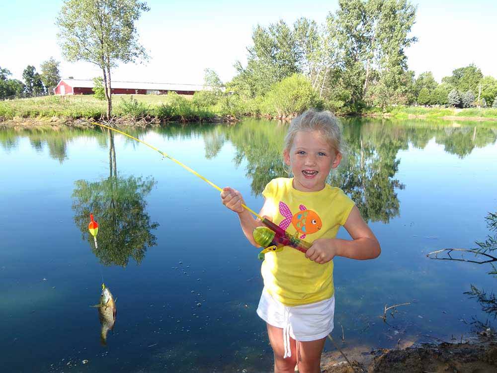 A kid holding a fishing pole with a fish at CAMP TURKEYVILLE RV RESORT