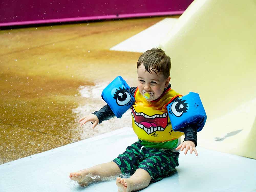 A baby boy sliding down a water slide at THE HILL CAMPGROUND