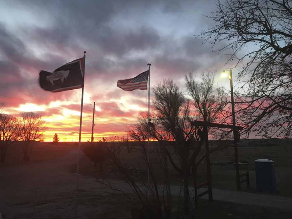 Two flags at dusk in the campsites at EL RANCHO VILLAGE RV & CABINS