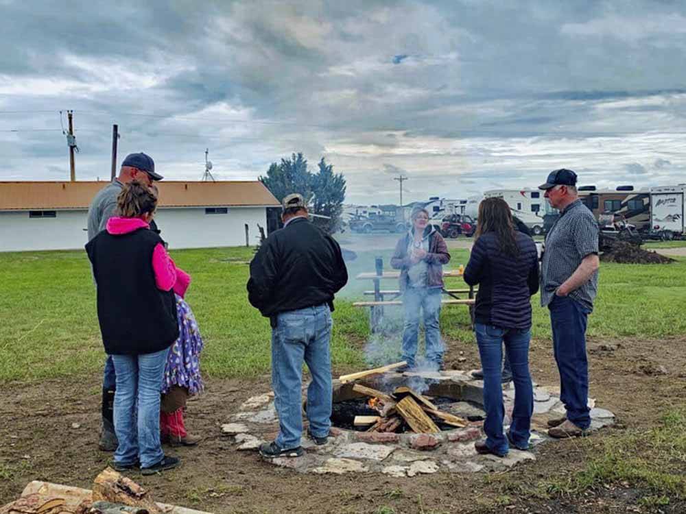 People standing around a fire pit at EL RANCHO VILLAGE RV & CABINS