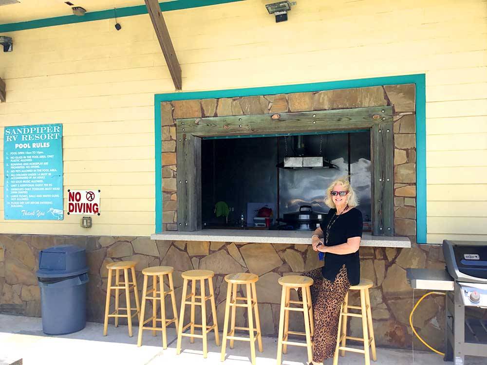 A woman in leopard pants standing in front of the snack bar at SANDPIPER RV RESORT