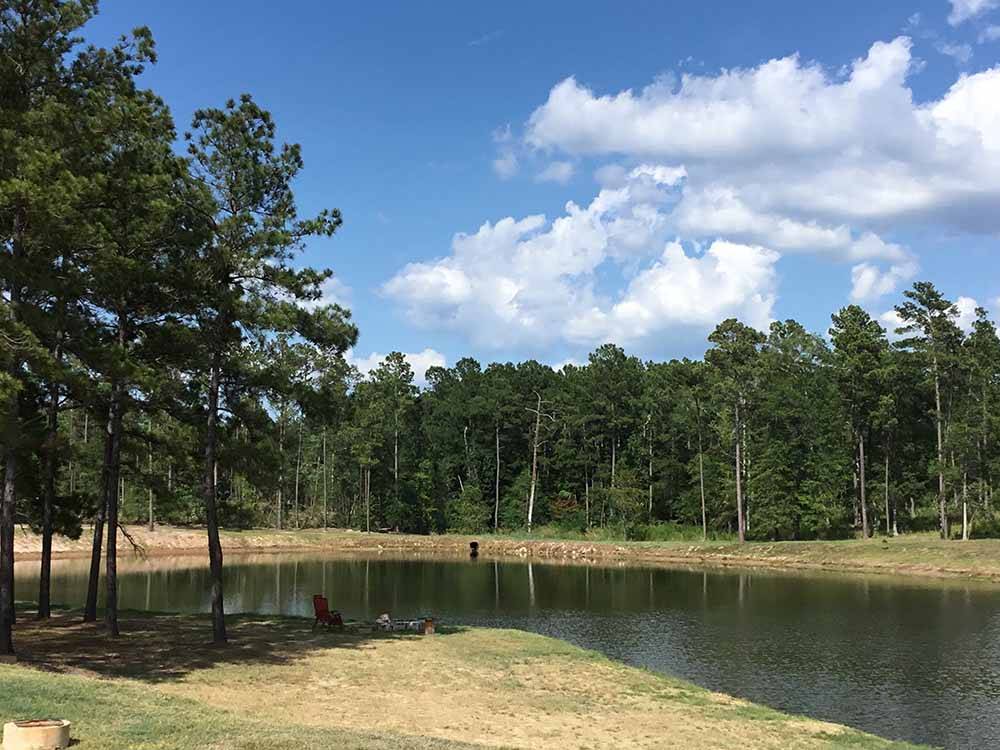 The lake surrounded by trees at BLUE SKY LAKE LIVINGSTON RV PARK & CABINS