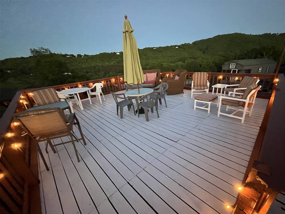 A deck with tables and chairs with lights on at PLUM NELLY RV PARK