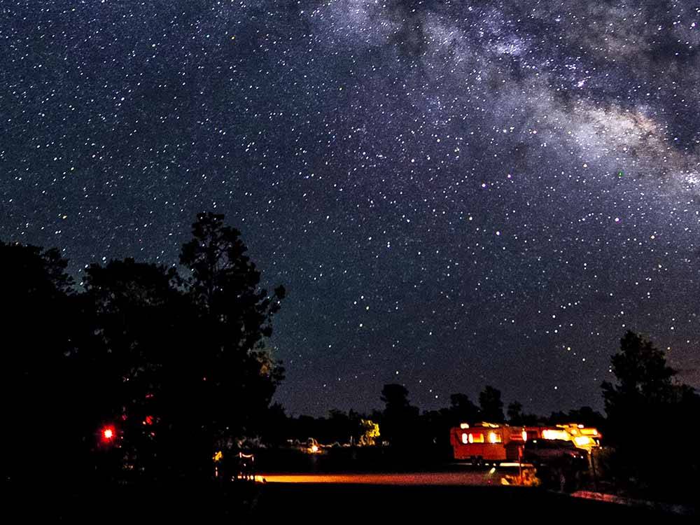 A motorhome parked under the starry night at PLUM NELLY RV PARK