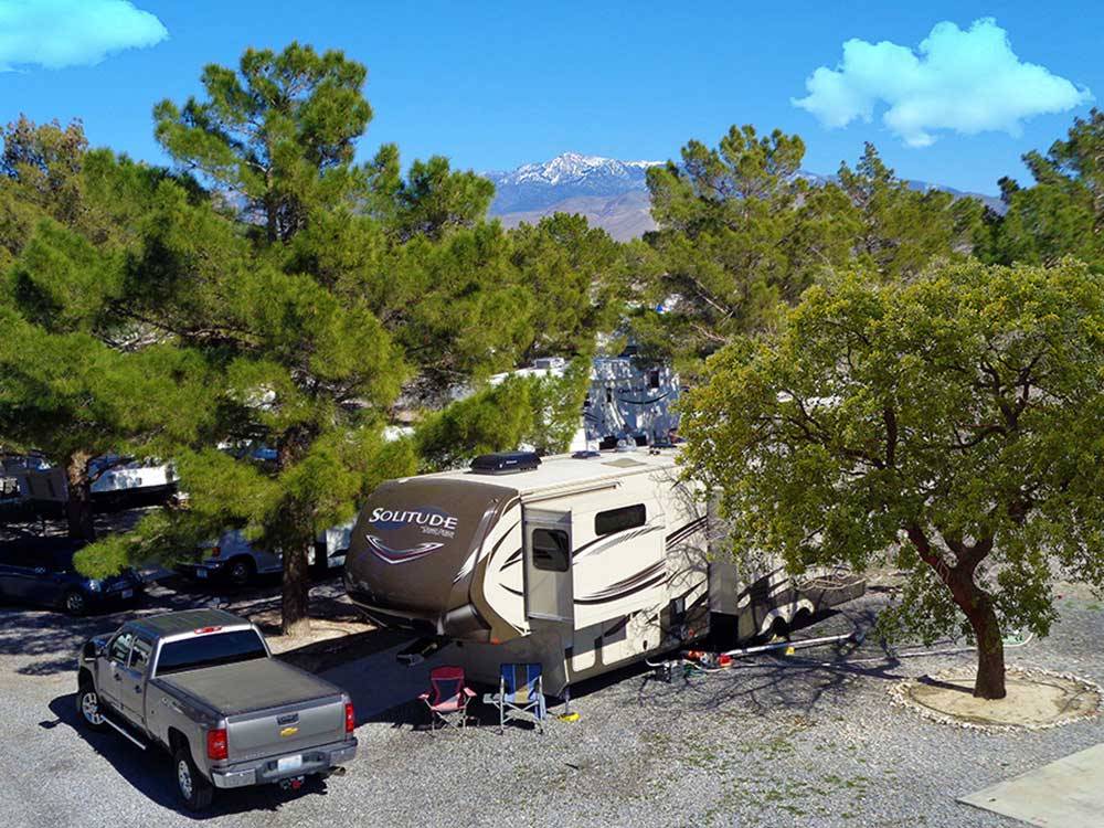 Trailer in a gravel site with pine trees at PREFERRED RV RESORT