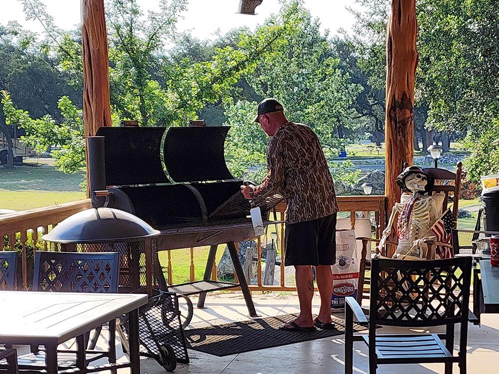 Man standing in front of a grill at LAKE MEDINA RV RESORT