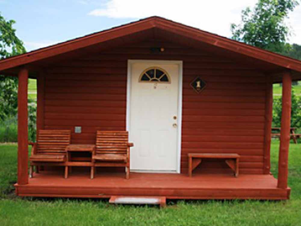 Red cabin with porch, white door and chairs at NO NAME CITY LUXURY CABINS & RV PARK