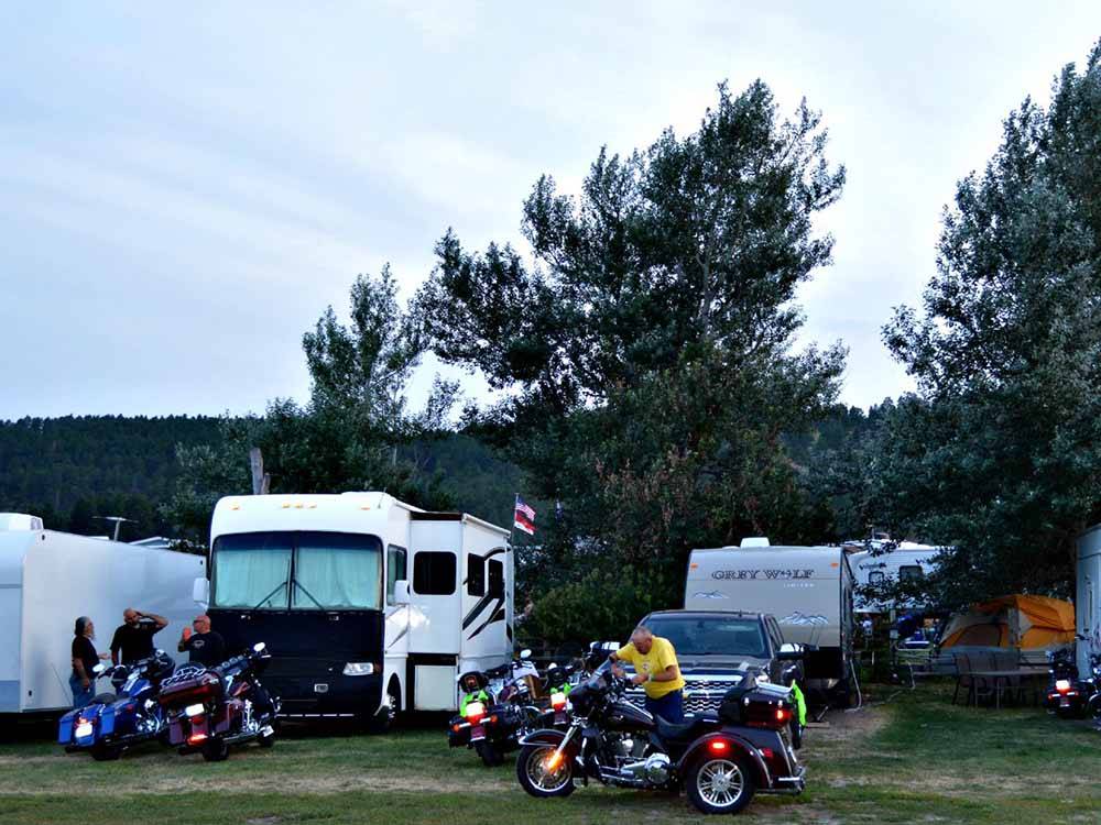 RVs in campsites with campers and their motorcycles at NO NAME CITY LUXURY CABINS & RV PARK