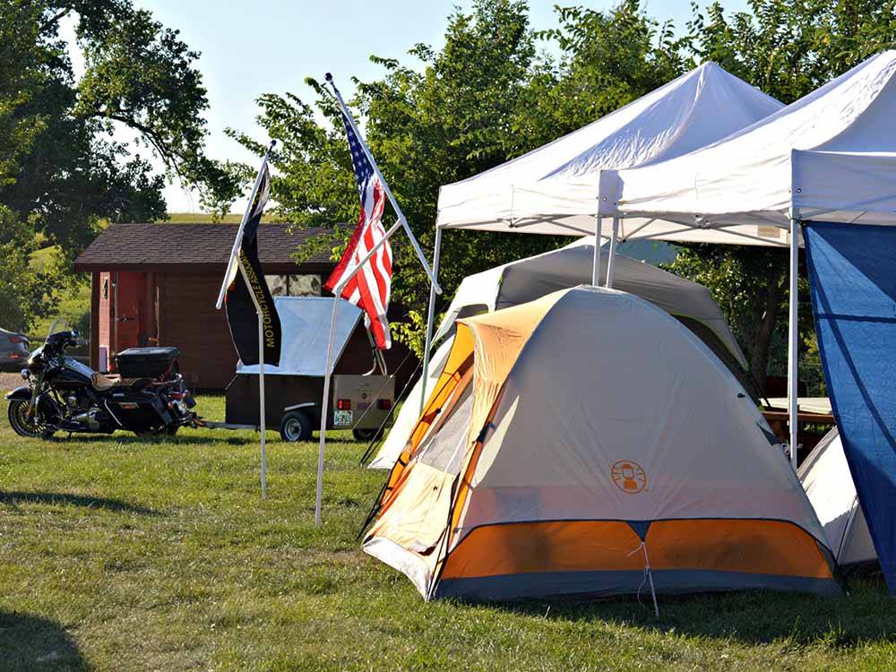 Campground tent area with flags, motorcycles at NO NAME CITY LUXURY CABINS & RV PARK