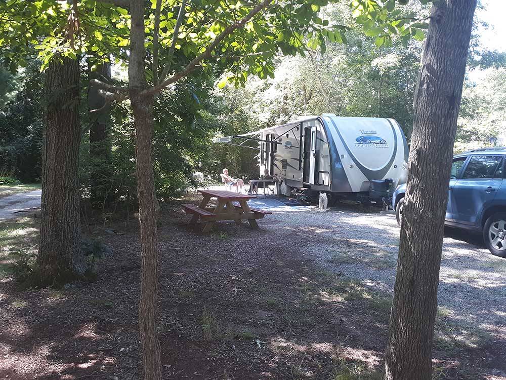 RV site in the trees with a trailer at DUNROAMIN' TRAILER PARK & COTTAGES