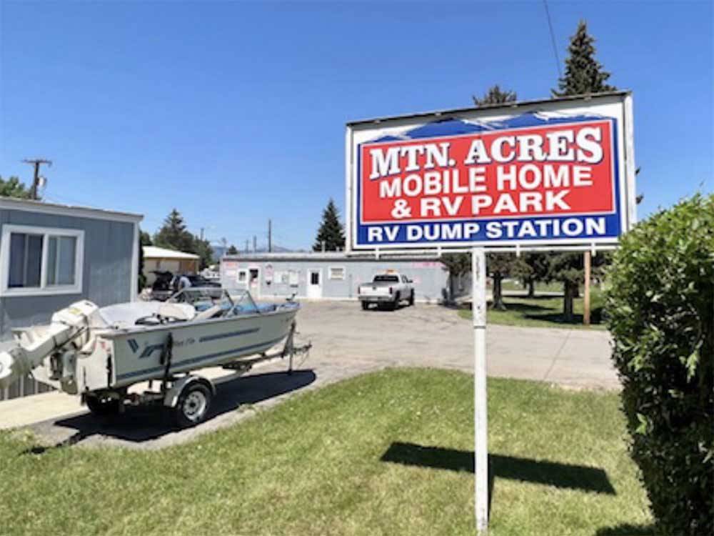 A boat parked next to the park sign at MOUNTAIN ACRES RV PARK