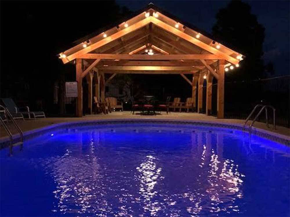 Pool at night near an a-frame canopy at RUSTIC MEADOWS RV PARK