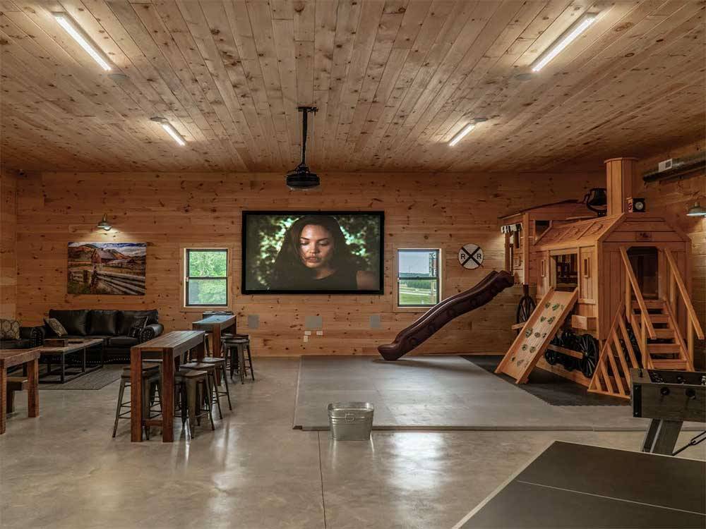 Big screen TV in rec room with play structure at RUSTIC MEADOWS RV PARK