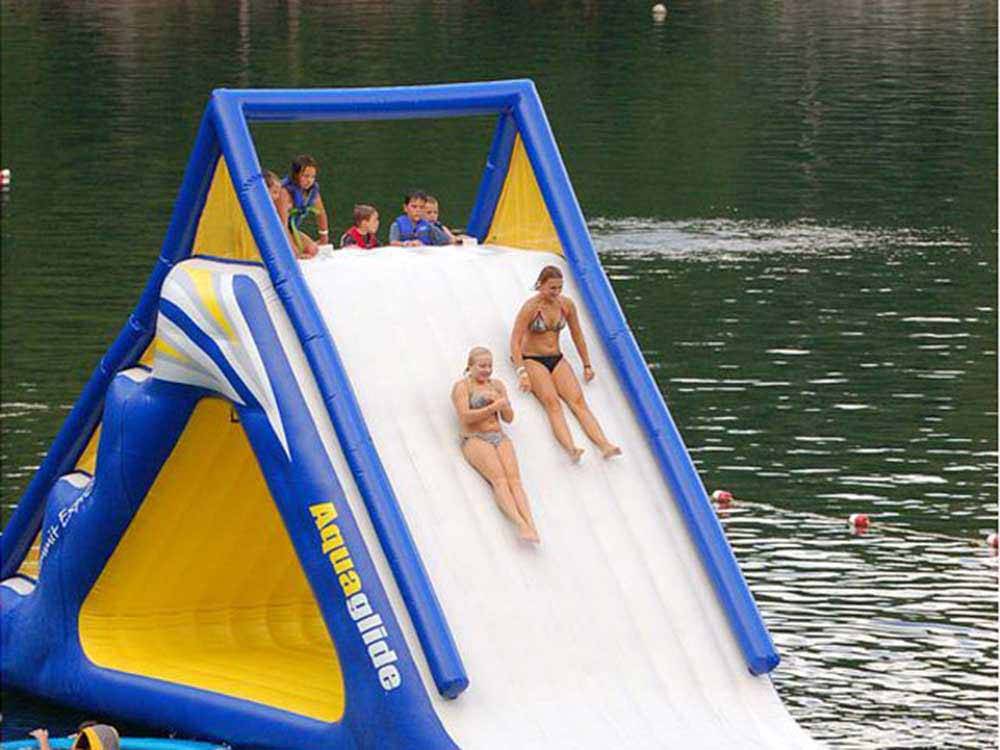 People sliding down large inflatable slide into the water at HIDDEN PARADISE CAMPGROUND