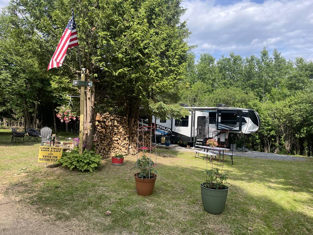 A shady RV site, firewood and flag