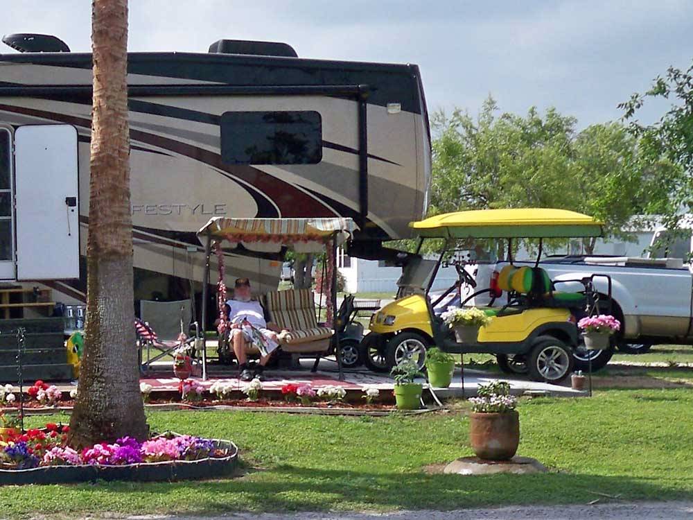 A man and golf cart by a motorhome at PALMDALE RV RESORT