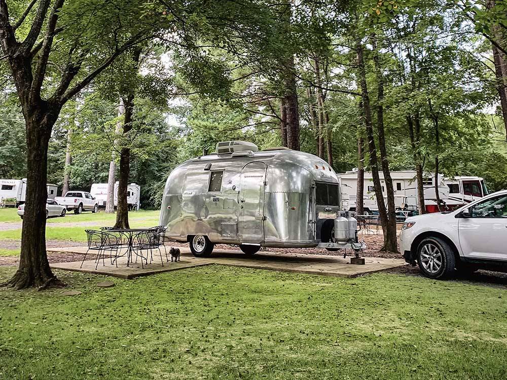 A small airstream trailer in a paved site at WENDY OAKS RV RESORT