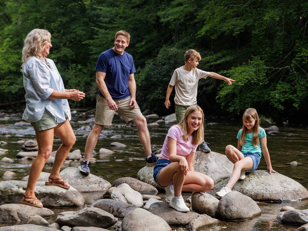 A family standing on rocks in a creek at Pigeon Forge Department Of Tourism