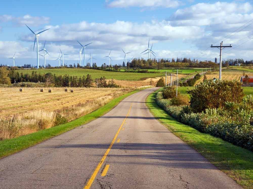 A road with large energy windmill to the side at PEI PROVINCIAL PARKS