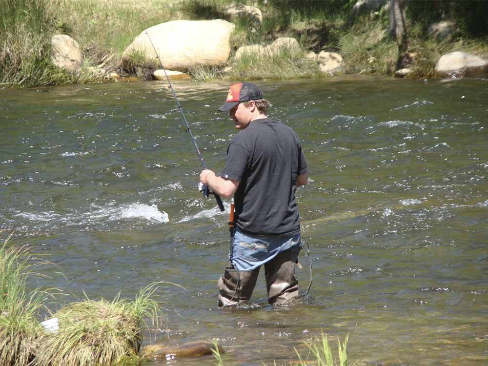 A man fishing while standing in the river at FRANDY PARK CAMPGROUND