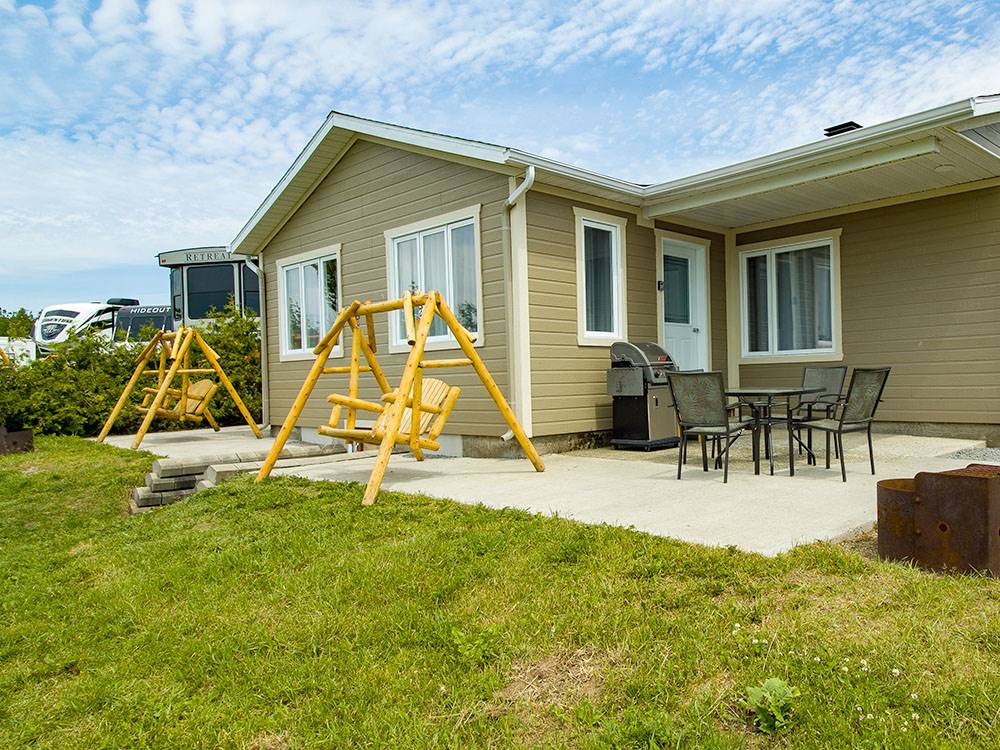 Rental cabin with swing and outdoor seating at Bas-St-Laurent Campground