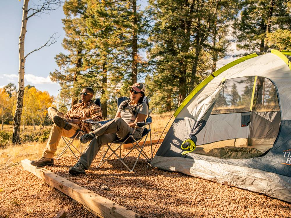 A couple sitting outside of their tent