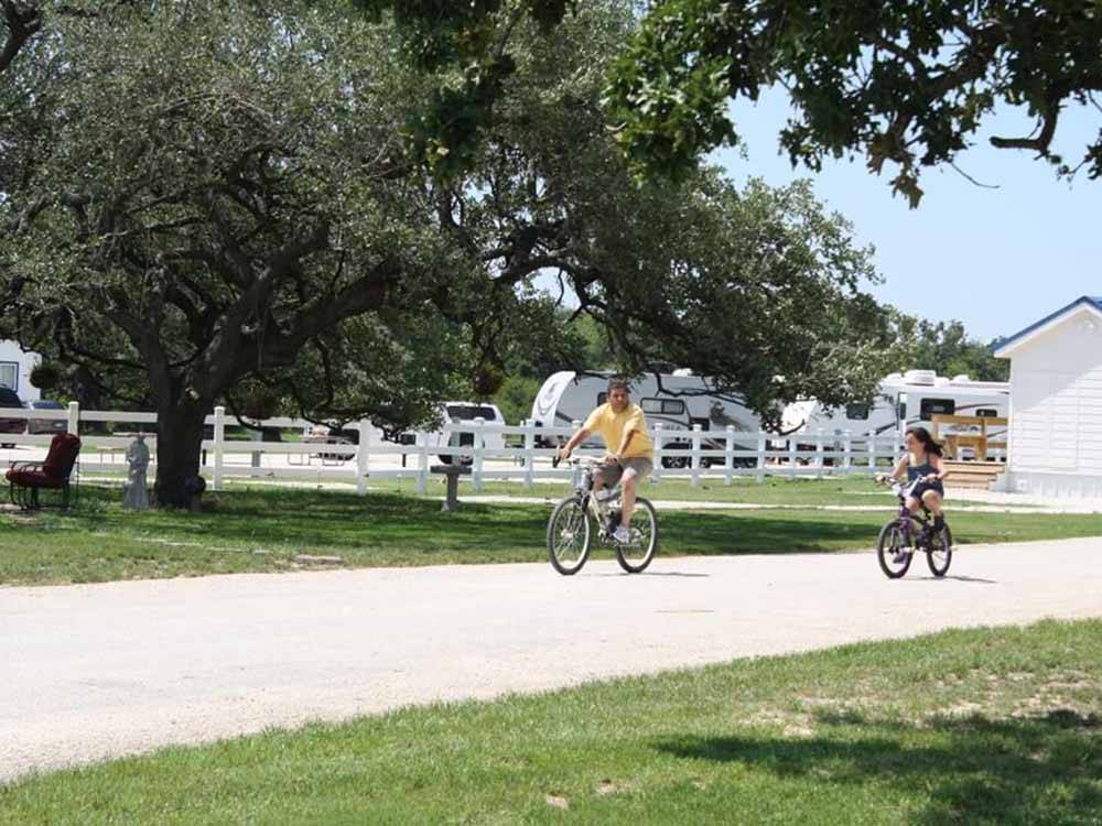 Two people riding their bikes on one of the roads at VICTORIA COLETO LAKE RV RESORT