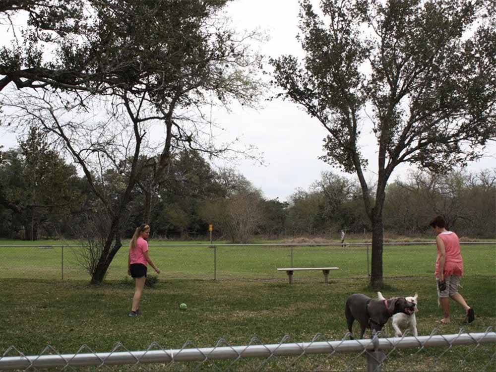 A girl and mom in the fenced in dog area at VICTORIA COLETO LAKE RV RESORT