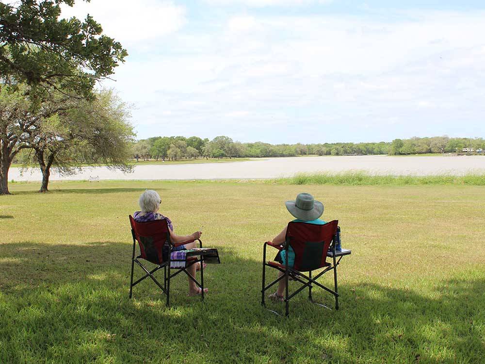 A couple of people sitting and looking at the water at BRACKENRIDGE RECREATION COMPLEX-TEXANA PARK & CAMPGROUND