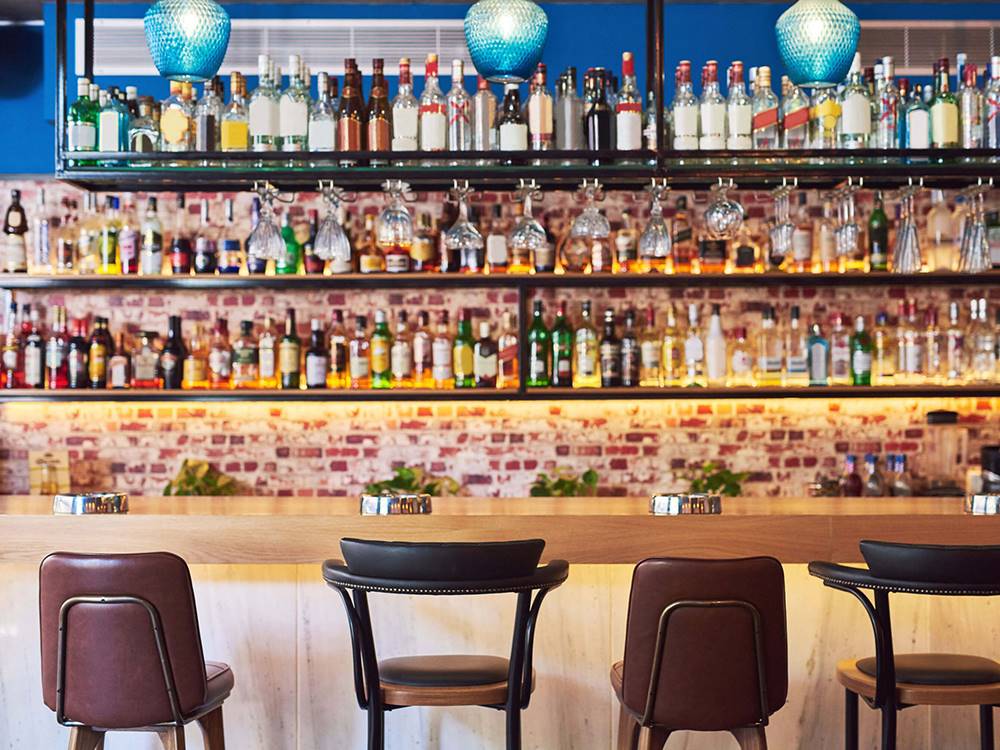 Bar and bar stools in front of shelves of bottles