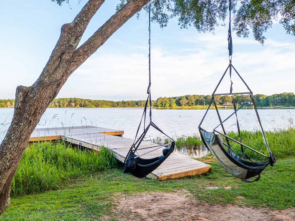 A dock and swinging chairs by the water at TWIN LAKES CAMP RESORT
