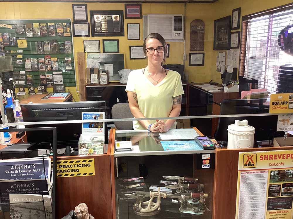 A woman standing behind the registration counter at SHREVEPORT/BOSSIER KOA JOURNEY
