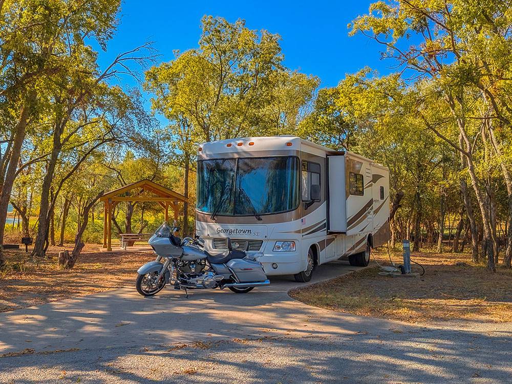 An RV and motorcycle parked in a paved site at Hidden Cove Park