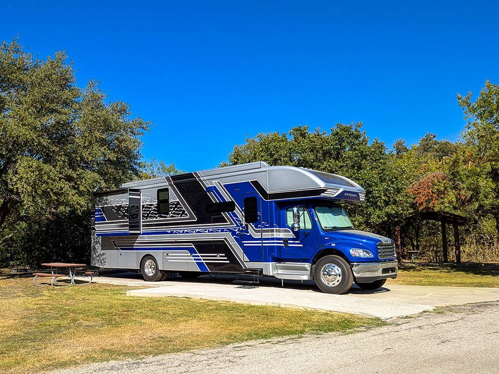 A blue and silver big rig RV parked in a paved site at Hidden Cove Park