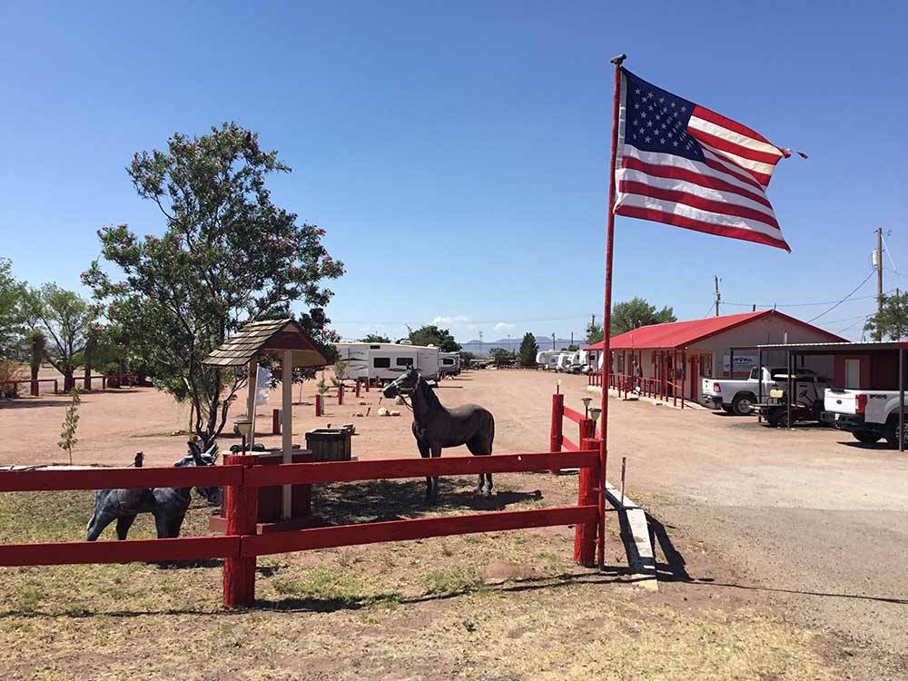 Landscaped area with US flag near entrance at WILD WEST RV PARK